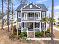Inviting two-story home with a charming front porch, classic columns, and well-manicured landscaping and blue siding at 3851 Sawyers Island Dr, Mount Pleasant, SC 29466