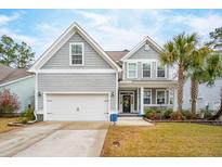 Charming two-story home with light gray siding, front porch, white trim, a two car garage and manicured front lawn at 5358 Birdie Ln, Hollywood, SC 29449
