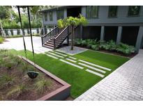Backyard landscaped with pavers, artificial grass, and a swing-set providing outdoor enjoyment and visual appeal at 219 Forest Trl, Isle of Palms, SC 29451