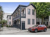 Charming two-story home featuring double balconies with black trim and a well-maintained yard and a brick driveway at 263 St Philip St, Charleston, SC 29403
