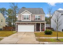 Charming two-story home featuring a stone facade, two-car garage, and a well-manicured front yard at 558 Wynfield Forest Dr, Summerville, SC 29485