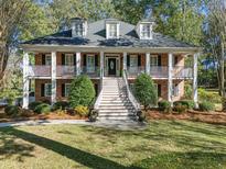 Charming two-story brick home with a double-decker porch, dormer windows, and beautifully landscaped front yard at 8608 Wild Bird Ct, North Charleston, SC 29420