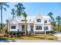 Charming two-story home with white siding, metal roof and lush landscaped yard at 105 Peninsula Dr, Ravenel, SC 29470