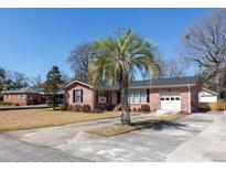 Charming red brick home featuring a one-car garage, well-manicured lawn, and complemented by a stately palm tree at 1258 Redeemer Dr, Hanahan, SC 29410