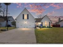 Charming home exterior featuring a two-car garage, manicured lawn and beautiful dusk sky at 135 Toura Ln, Charleston, SC 29414