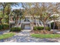 Charming townhomes featuring garages, elevated entryways, and lush landscaping create a welcoming facade at 1902 Long Bend Dr # 1B, Seabrook Island, SC 29455