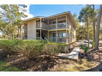 Inviting condo exterior showcasing a private deck nestled among lush greenery and mature trees at 214 Sea Cloud Cir, Edisto Island, SC 29438