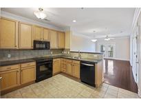 Traditional kitchen with wood cabinets, black appliances, and a view into the adjacent living room at 2244 Ashley Crossing Dr # 1236, Charleston, SC 29414