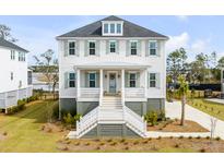 Stunning two-story home features white siding, sage shutters, and an inviting front porch with marsh views at 3554 Clambank Dr, Mount Pleasant, SC 29466