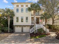 Stunning three-story home with a beautiful brick driveway, two-car garage, and lush tropical landscaping at 4008 Cameron Blvd, Isle of Palms, SC 29451