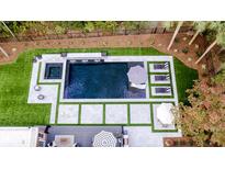 Aerial view of a modern pool, hot tub, lounge chairs, umbrellas, and green landscaping creating a backyard oasis at 4312 Club Course Dr, North Charleston, SC 29420