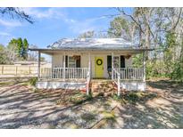 Charming home featuring a welcoming front porch, bright yellow door, and metal roof at 130 Tupperway Dr, Summerville, SC 29483