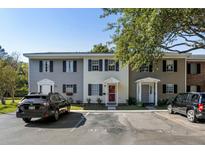 A cozy two-story townhome showcasing a red door, black shutters, and parking spaces in front of the unit at 303 Lakeside Dr # C-2, Mount Pleasant, SC 29464