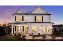Charming two-story home with a welcoming front porch and manicured landscaping at dusk at 325 Abercom Place Dr, Moncks Corner, SC 29461