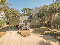 Charming coastal home featuring a welcoming front porch and stilt foundation and lush landscaping at 3323 Myrtle St, Edisto Island, SC 29438