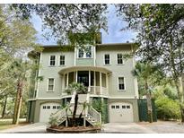 Inviting exterior of home featuring double garages, palm trees, and a staircase to a welcoming front porch at 6021 Jibe Ct, Awendaw, SC 29429
