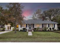 Charming brick home featuring a manicured front lawn, symmetrical windows, and lush landscaping at 105 Chadwick Dr, Charleston, SC 29407