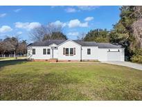 Charming single-story home with a well-maintained lawn, attached garage, and classic white siding at 1409 Main St, Bonneau, SC 29431