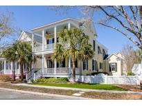 Charming two-story yellow home with white porch railings and palm trees lining the front at 1676 Paradise Lake Dr, Mount Pleasant, SC 29464