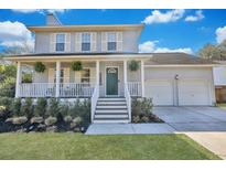 Charming two-story home featuring a welcoming front porch with hanging plants and a well-manicured lawn at 2029 Country Manor Dr, Mount Pleasant, SC 29466