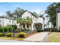 Charming two-story home with landscaped yard, palm trees, wooden fence, and light-colored driveway at 1095 Bexley St, North Charleston, SC 29405