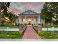 Stunning two-story home featuring classic architectural details, a brick walkway, and an expansive front lawn at sunset at 1714 Middle St, Sullivans Island, SC 29482