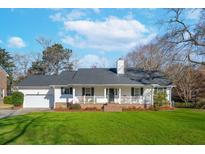 Charming one story home with a brick porch, white railings, and a well-manicured lawn at 2416 Pleasant Garden Dr, Charleston, SC 29414