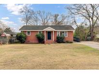 Charming single-story brick home featuring a well-manicured lawn, blue sky, and mature trees at 4203 Marilyn Dr, North Charleston, SC 29418