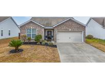 Charming brick home with a well-manicured lawn, attached garage, and inviting curb appeal at 7720 Kinston St, North Charleston, SC 29418