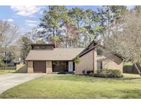 Charming home featuring a brick and wood exterior with a well-manicured lawn and an attached garage at 107 Four Iron Dr, Summerville, SC 29483