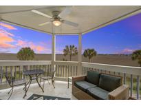 This covered patio features a seating area with views of tropical trees and marshy landscape at sunset at 134 Marsh View Villas, Folly Beach, SC 29439