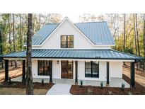 Charming two-story home with a metal roof, wood porch columns, and meticulously landscaped front yard at 143 Harvest Way, Walterboro, SC 29488