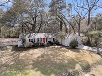 Charming single story home with mature landscaping, long driveway, and bright red front door at 1521 Lynton Ave, Charleston, SC 29412