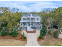 Stunning two-story home with double porches, mature landscaping, and a spacious driveway nestled in a lush, tree-filled yard at 3204 Waterway Blvd, Isle of Palms, SC 29451
