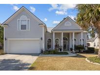 Charming home featuring a two-car garage, manicured lawn, and inviting front porch with white columns at 9394 Harroway Rd, Summerville, SC 29485