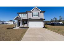Gorgeous two-story home with gray siding, two car garage, charming curb appeal, and well-kept lawn at 112 Edisto Crossing Ct, Ridgeville, SC 29472