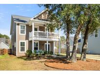Charming two-story home featuring a double front porch, swing, and well-manicured lawn at 1532 Roustabout Way, Charleston, SC 29414