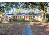 Charming brick home featuring a well-manicured lawn and beautiful mature trees at 1595 Dickens St, Charleston, SC 29407
