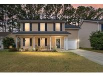 Charming two-story home featuring a welcoming front porch and manicured lawn at dusk at 215 Trickle Dr, Summerville, SC 29483