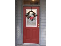 Charming red front door adorned with a festive holiday wreath and a modern doorbell camera system at 3406 Mariners Way Way, Moncks Corner, SC 29461