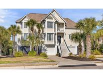 Charming coastal home featuring double garages, palm trees, and a welcoming staircase to the front door at 65 Ocean Point Dr, Isle of Palms, SC 29451