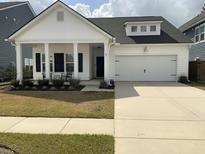 Charming one-story home featuring a covered porch, black shutters, and a two-car garage at 87 Morning Song St, Summerville, SC 29485