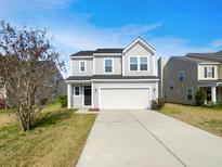 Charming two-story home with a well-manicured lawn and a spacious driveway leading to an attached two-car garage at 1343 Hermitage Ln, Ladson, SC 29456