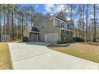 Charming two-story home with gray siding, stone accents, long driveway, and attached two-car garage at 3000 Flat Rock Ln, Ridgeville, SC 29472