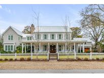 Charming two-story home with a white picket fence, large porch, and neatly manicured landscaping at 1010 Tall Pine Rd, Mount Pleasant, SC 29464