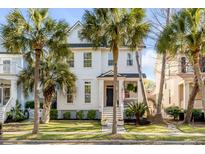 Charming two-story white home with a welcoming front porch, complemented by lush palm trees and well-manicured landscaping at 126 Etiwan Park St, Charleston, SC 29492