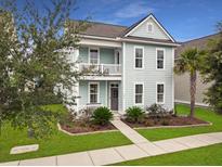 Charming two-story coastal home with a welcoming front porch, balcony, manicured lawn, and lush landscaping at 1841 Gammon St, Charleston, SC 29414