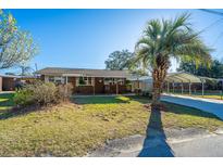 Charming brick home featuring a covered porch, mature palm tree and a carport at 5410 Boots Ave, North Charleston, SC 29406