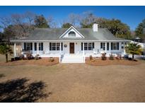 Charming home with a welcoming front porch, mature landscaping, and a manicured lawn at 6118 Hazelhurst Ln, Ravenel, SC 29470