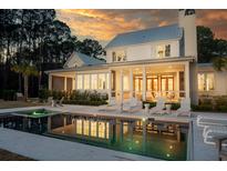 Stunning backyard featuring a modern pool with lounge chairs and a covered porch with outdoor seating at twilight at 821 Bulls Bay Blvd, Mount Pleasant, SC 29429